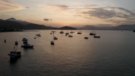 Luftaufnahme-Von-Yachten,-Booten-Und-Segelbooten,-Die-Bei-Einem-Wunderschönen-Sonnenuntergang-In-Der-Nähe-Einer-Brasilianischen-Küste-Vor-Anker-Liegen