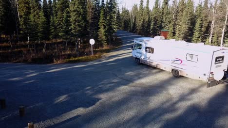 Aerial,-drone-shot,-following-a-camper-van-and-a-trailer,-driving-on-a-road,-surrounded-by-spruce-forest,-near-Johnson-lake,-in-Kenai-Peninsula-of-Alaska,-United-states-of-america