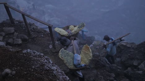 Kawah-Ijen-sulphur-mining-worker-hiking-the-rocky-terrain-carrying-heavy-loads-in-early-morning-light