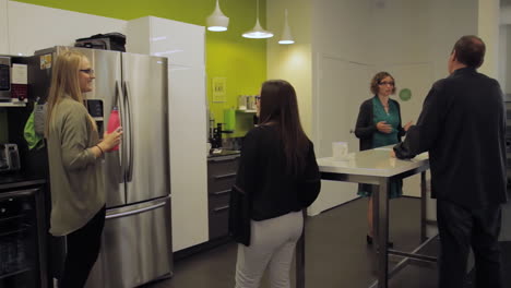 Co-workers-talking-in-a-modern-office's-kitchen