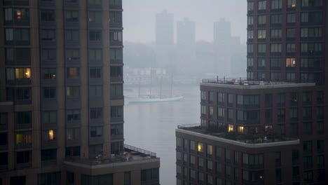 Thick-fog-distorts-the-view-through-skyscrapers-at-a-huge-old-sail-boat-anchored-on-the-Hudson-River-during-Sail-Festival