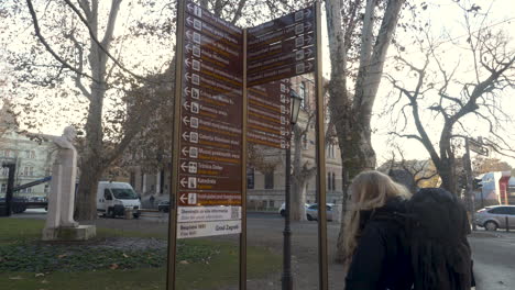 Backpacking-girl-looking-at-signs-with-different-directions-in-Zagreb