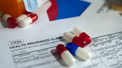 Prescription-drug-bottle-and-pills-spilling-onto-a-patient-health-insurance-claim-form