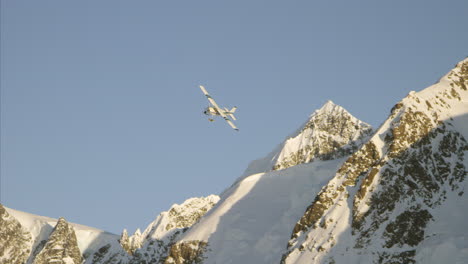 Airplane-flies-low-over-snow-covered-mountain-past-moon