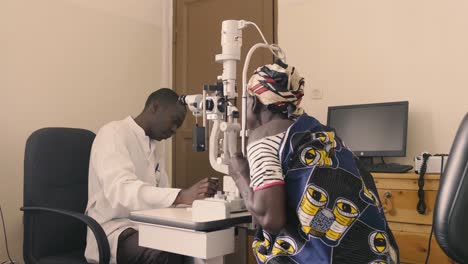 African-Doctor-checking-eye-sight-of-patient-in-eye-hospital-and-doctor-moving-equipment-and-setting-head-of-patient-on-the-correct-place-for-adjustments