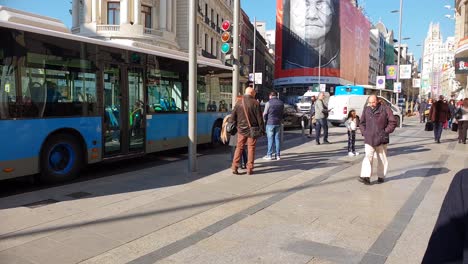 Traffic-on-Gran-Via-In-Downtown-Madrid-city,-buses-cars-and-pedestrians-pass-by