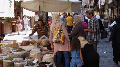Man-selling-varieties-of-nuts-and-is-surrounded-by-his-customers-in-a-bazaar-in-damascus