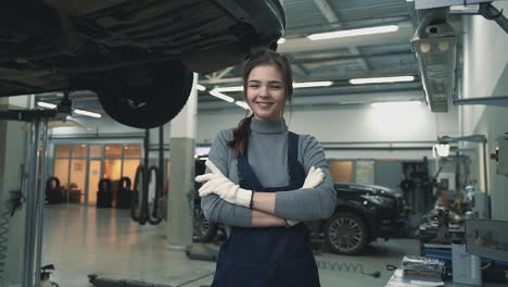 Mechanic-young-female-posing-and-looking-at-camera-in-a-car-workshop.-International-Women's-Day.