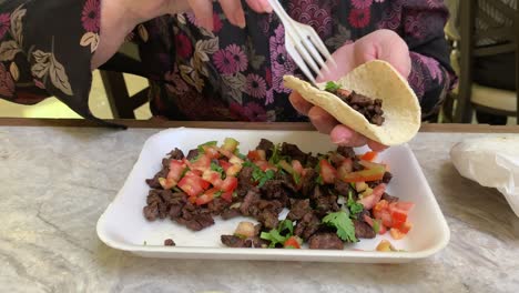 Older-woman-putting-hot-sauce-in-a-beef-taco