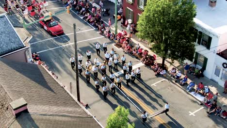 Close-up-aerial-of-marching-band-during-parade-in-Small-Town-America,-people-line-the-sidewalks
