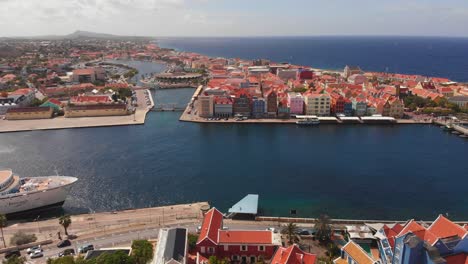 Epic-revealing-aerial-of-Willemstad,-Curacao-with-a-cruise-ship-docked-in-Sint-Anna-Bay