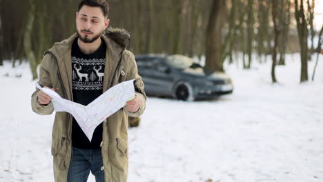 Caucasian-man-checking-map-for-directions-in-a-snowed-forest.
