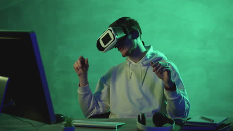 Young-man-using-a-VR-headset-and-a-computer-on-a-colorful-background