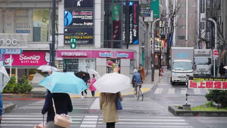 Pedestrians-with-umbrellas-crossing-a-crosswalk-in-the-rain-in-downtown-Tokyo,-Japan