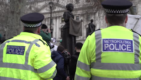 Two-police-officers-stand-and-watch-a-protest-next-to-the-statue-of-Suffragette-Dame-Millicent-Fawcett-on-Parliament-Square