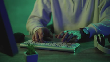 Male-hands-typing-on-the-keyboard-working-with-a-computer-on-a-green-colorful-background.-Close-up.