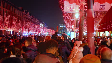 New-year-celebration-event-in-Paris-Street-Champs-Élysées-few-moment-before-light-will-go-on-red-light-covered-street-with-mass-crowded-people-around-waiting-captured-in-4k