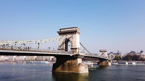 Static-shot-of-Budapest-Chain-bridge-with-people-walking-on-it-and-boats-in-Danube-river