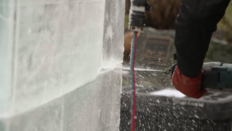 Slide-left-on-ice-sculptor-cutting-ice-blocks-with-reciprocating-saw,-Slow-Motion