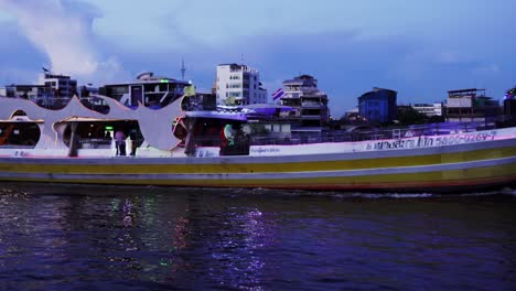 Tourist-ferry-on-the-Chao-Phraya-river-in-Bangkok-at-night,-Thailand