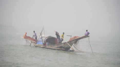 Bangladeshi-fisherman-is-spreading-nets-in-the-river-trying-hard-to-control-the-boat
