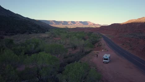 Aerial-shot-of-man-next-to-RV-boondocking-outside-Zion-National-Park,-Utah