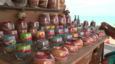 Still-wide-shot-of-sand-art-jars-in-a-vendor-stall-with-a-man-sitting-nearby