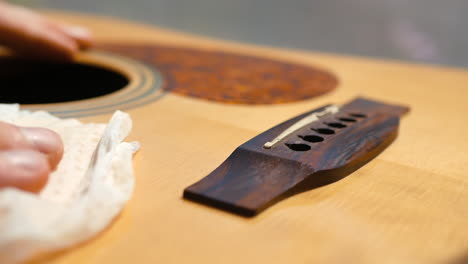 Musician-cleaning-and-oiling-an-acoustic-guitar-neck-and-body