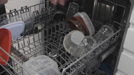 Medium-shot-of-a-man's-arms-picking-glasses-out-of-a-dishwasher-to-put-them-away