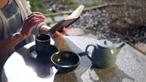 Close-up-on-a-woman-reading-a-book-and-drinking-a-hot-cup-of-herbal-green-tea