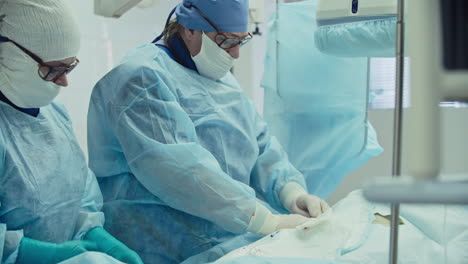 Cirujano-Masculino-Y-Femenino-En-Vestido-Azul-Operando-En-Un-Quirófano