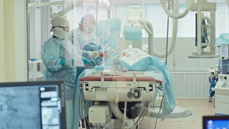 Outside-view-of-an-operating-room,-two-surgeons-operate-on-a-patient-lying-on-hospital-bed