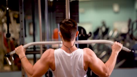 Rear-closeup-of-young-bodybuilder-doing-lat-pulldowns-on-a-machine