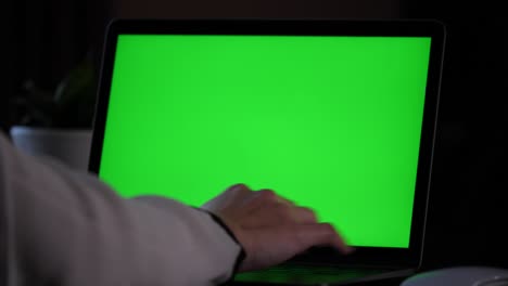 Hands-in-white-shirt-types-on-keyboard,-pointing-with-finger-a-text-on-green-screen-on-a-laptop-screen,-continuing-typing
