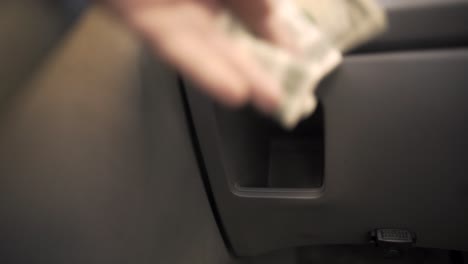 POV-perspective-of-quickly-grabbing-cash-from-a-compartment-in-a-generic-grey-car