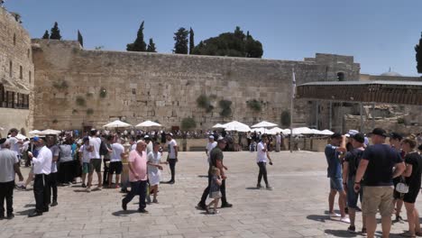 Tilt-down-shot-of-pilgrims-gathering-by-Western-Wall-in-Jerusalem-for-praying