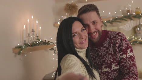 Loving-caucasian-couple-taking-a-selfie-video-and-waving-at-camera-on-Christmas-at-home