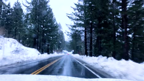 Dramatic-Time-lapse-shot-of-a-car-as-it-travels-through-Snow,-snowy-mountains,-Pine-trees-in-winter,-other-vehicles-can-been-seen-in-the-adjoining-lanes