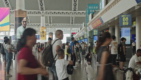 Time-lapse-of-Guangzhou-high-speed-train-South-railway-station-waiting-hall,-with-numerous-passengers-passing-by-and-sitting-on-the-seats,-Guangzhou,-China