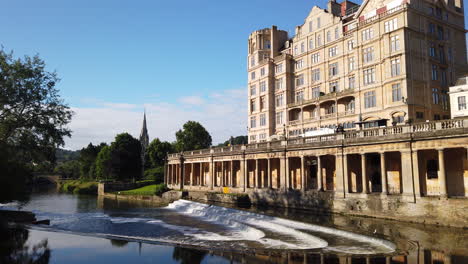 Static-Slow-Motion-Shot-of-Pulteney-Weir-and-the-Empire-Hotel-in-Bath,-Somerset-on-Beautiful-Summer’s-Morning-with-Blue-Sky-and-Golden-Light