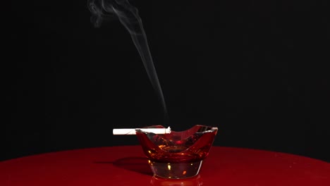 Rauchende-Zigarette-Isoliert-Auf-Dunklem-Hintergrund,-Brennen-Im-Aschenbecher,-Konzept-Zur-Raucherentwöhnung