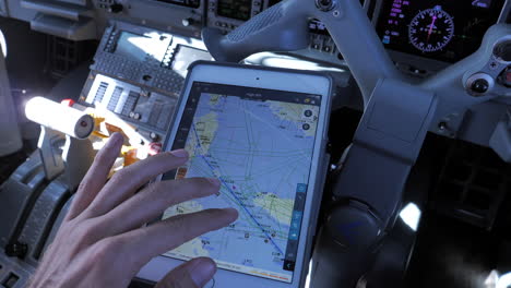 Ein-Pilot-Nutzt-Ein-Tablet-Auf-Seinem-Knie-Im-Cockpit-Eines-Flugzeugs,-Um-Während-Des-Fluges-Die-Route-Zu-überprüfen