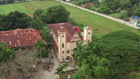 Aerial-View-of-a-Catholic-Church-in-the-Philippines-with-Crowd-Near-Entrance-in-4K