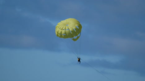 A-couple-doing-parasailing-descends-hunged-up-a-yellowish-parachute