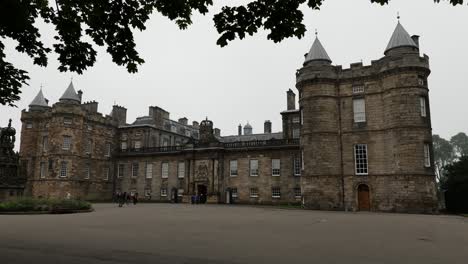 The-courtyard-of-the-Holyrood-Palace,-royal-residence-in-Edinburgh,-Scotland-with-trees-at-the-top-of-the-image-framing-the-castle