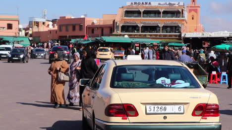 Belebte-Straße-In-Marrakesch,-Marokko,-Mit-Menschen,-Die-Den-Vorbeifahrenden-Verkehr-Aufhalten