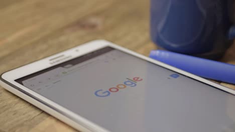 Google-homepage-and-logo-displayed-on-tablet-with-drink-and-pen