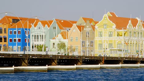 People-Walking-At-The-Queen-Emma-Bridge-With-Colorful-Buildings-In-The-Background-On-A-Sunny-Day-In-Punda,-Curacao