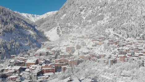 Aerial-Zoom-Out-Dolly-shot-of-Sunlight-hitting-Old-Manali-town-in-the-morning-covered-with-white-snowflakes-after-receiving-a-heavy-snowfall-during-the-winters-of-2020,-shot-with-a-drone-in-4k