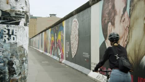 Cámara-Lenta-De-Mujer-En-Bicicleta-En-La-Galería-Del-Lado-Este-En-El-Muro-De-Berlín